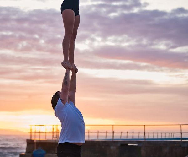 Silhouette of a couple doing a yoga pose against a sunset backdrop.